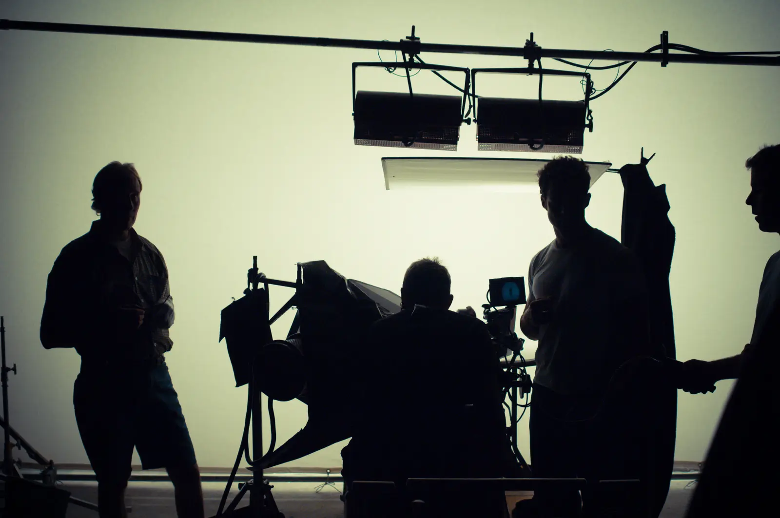 Silhouettes of a film crew on a studio set, lighting rig overhead