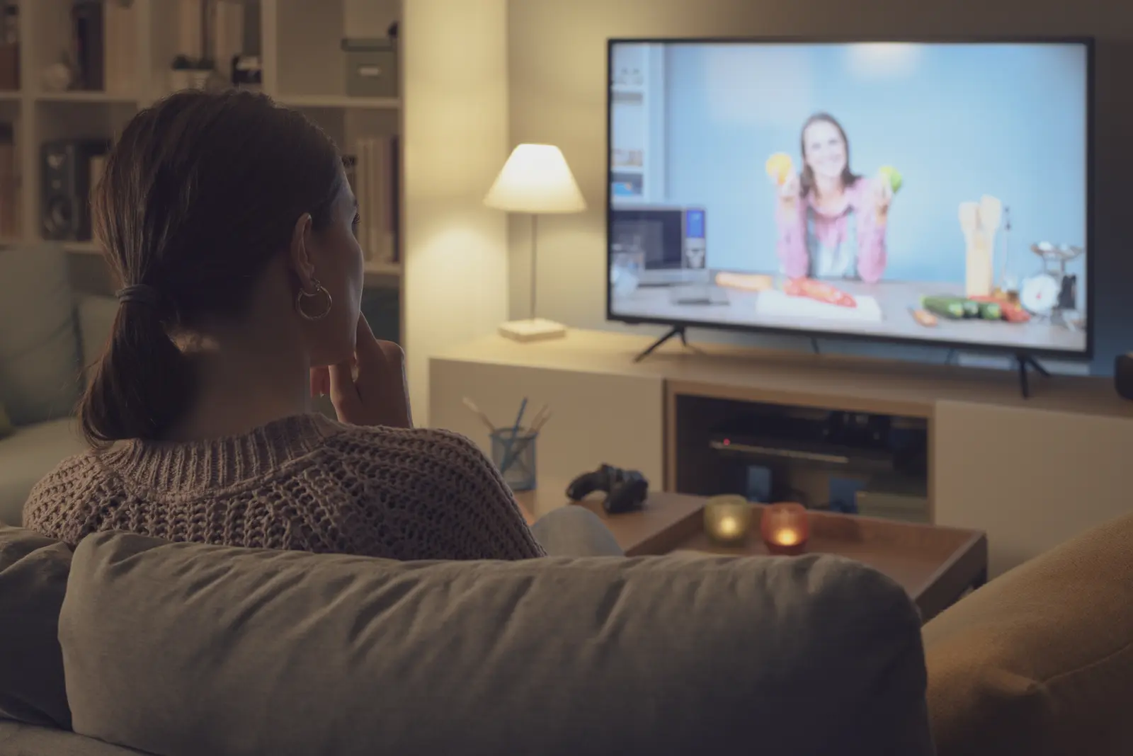 Woman watching a TV cooking show in a living room at evening