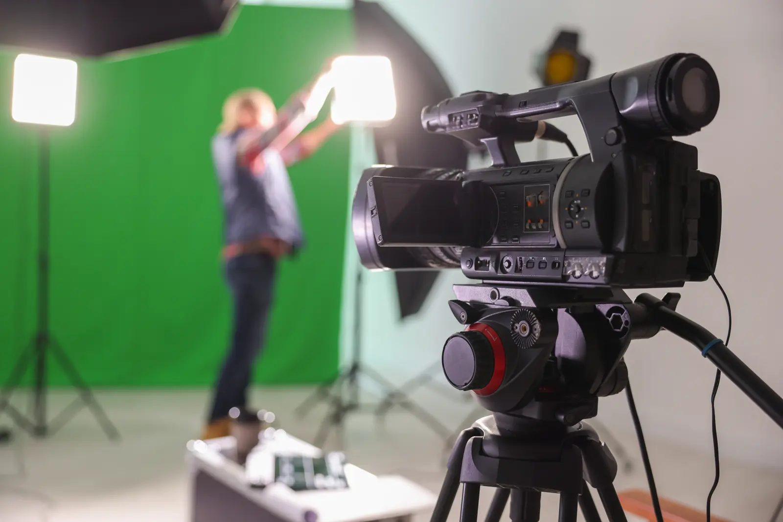 Professional video camera on tripod in front of a green screen with a presenter