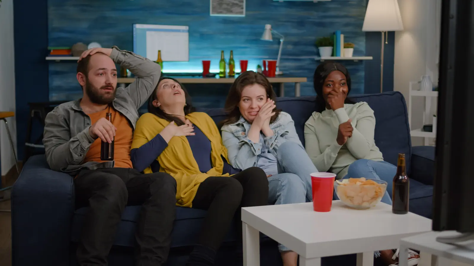 Group of friends watching TV together on a couch in a living room